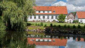 Kirke-HvalsøSonnerupgaard Hotel & Konference的河边的白色房子,有红色屋顶