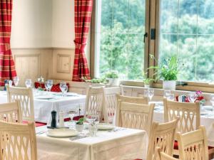 Thiergarten纽姆勒高萨湖酒店的一间设有白色桌椅和窗户的用餐室