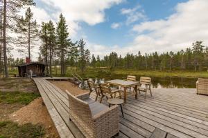 萨利色尔卡Kuukkeli Log Houses Villa Aurora "Pupula"的湖畔木甲板上配有桌椅