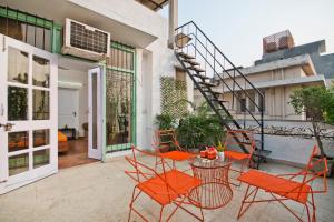 新德里Prakash Kutir B&B的户外庭院配有橙色椅子和桌子