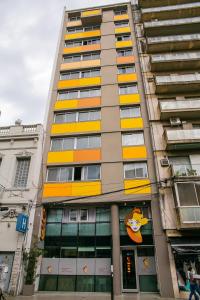 罗萨里奥罗伯塔罗莎德丰塔纳套房酒店的一座高大的建筑,设有黄色和橙色的窗户