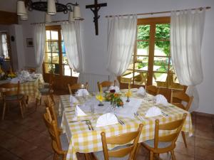 EurasburgLandgasthof Berg的用餐室配有带黄白色桌布的桌子