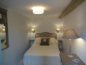 圣加蒂安代布瓦帕格力旅馆的一间卧室配有一张带台灯和桌子的床