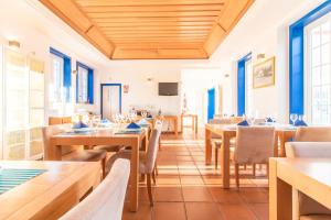 劳塞尔Hotel Lousal的餐厅设有木桌、椅子和蓝色窗户。