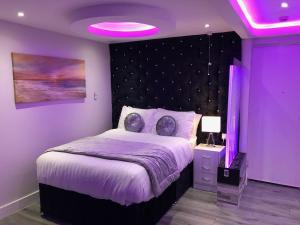 布雷得佛莱维特服务公寓的紫色卧室配有一张床和紫色照明