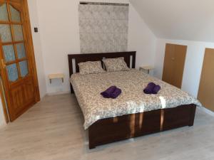 VecmuižaViesu nams Purenes的一间卧室配有一张床,配有两张紫色拖鞋