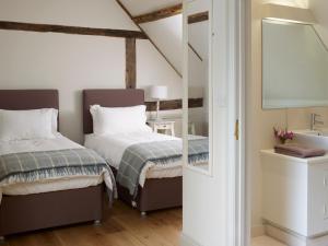 Hampstead NorrisManor Farm Courtyard Cottages的一间卧室设有两张床、一个水槽和镜子