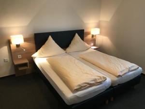 Knüllwald赫伯特汽车旅馆的一间卧室配有一张带两个枕头和两个灯的床。