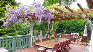 圣保罗恩查拉L'OURSERIE Bed & Breakfast的紫色紫藤甲板上的木桌和椅子