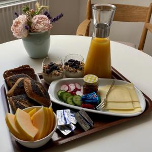 JellingBirgittes B&B i Jelling的桌上的带面包和橙汁的食品托盘