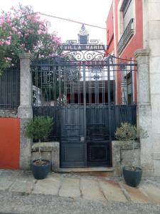 Fuentes de BéjarHotel Villa Maria的建筑前有盆栽植物的黑色门