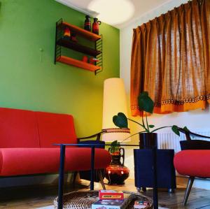 OlstRetro-huisje GoedFout的客厅设有红色沙发和绿色墙壁。