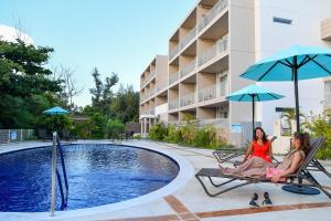 恩纳Odysis Onna Resort Hotel的两个女人坐在游泳池旁的椅子上