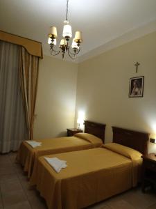 圣乔瓦尼·罗通多casapaceebene的酒店客房设有两张床和吊灯。