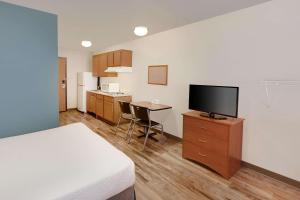 康瑟尔布拉夫斯WoodSpring Suites Council Bluffs的配有一张床和一台平面电视的酒店客房