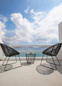 圣斯特凡诺斯Obsession Mykonos的阳台上配有两把椅子和一张桌子,享有海景