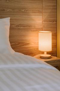 乌隆他尼The Cape Hotel的一张带灯的白色床,放在床头柜上
