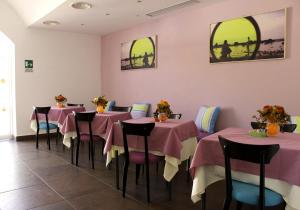 兰佩杜萨欧夏酒店的一间餐厅,房间内设有粉红色的桌子和椅子