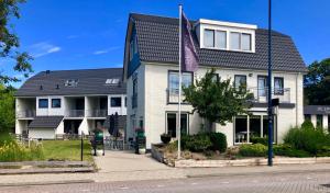 德科赫Boutique Hotel de Zwaluw的前面有紫色旗帜的白色房子