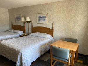 BurkesvilleRiverfront Lodge的酒店客房,设有两张床和一张桌子及椅子