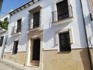 隆达Casa Candela的白色的建筑,设有黑色的门和阳台