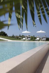特罗佩阿Il Borghetto Creative Resort的一个带白色椅子和遮阳伞的游泳池