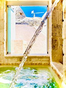 阿尔贝罗贝洛Trulli Antichi Mestieri - Widespread Trulli in the historic center的水管从有窗户的建筑物里出来
