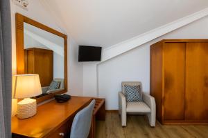 Rosário-Lagoa阿坎约酒店的客房设有书桌、镜子和椅子。