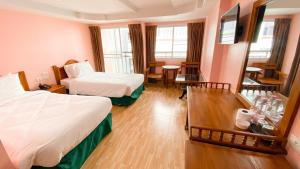 芭堤雅市中心A.A. Pattaya Golden Beach Hotel的酒店客房设有两张床和一张桌子。