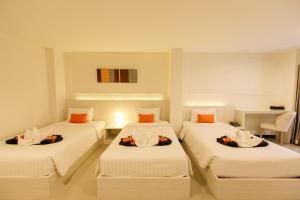 清莱德哈哥公寓酒店 的配有白色床单和橙色枕头的三张床