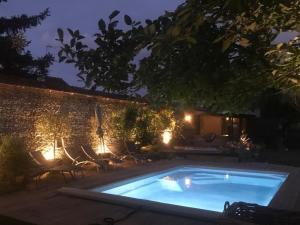 贝叶La Paresse en Ville的夜间游泳池,带椅子和砖墙