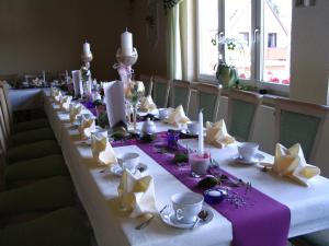 施泰纳赫斯科恩奥西赫特酒店的长桌,带白色和紫色盘子和杯子
