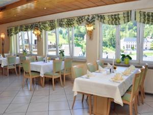 施泰纳赫斯科恩奥西赫特酒店的餐厅设有白色的桌椅和窗户。