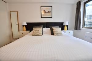 伦敦伦敦金融城马林公寓的一间卧室配有一张带两盏灯的大型白色床。