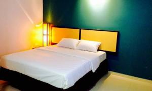关丹Senrose Hotel Kuantan的一间卧室设有一张白色大床和绿色的墙壁