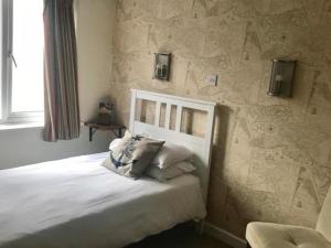 考斯The Anchor Inn的卧室配有白色的床铺和石墙