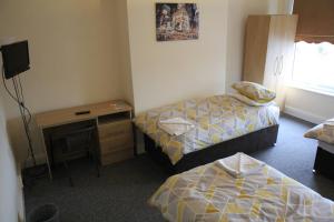 利物浦Clifton arms的客房设有两张床、一张桌子和一台电视。
