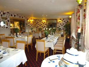 TarlandThe Commercial Hotel的一间设有白色桌椅和鲜花的餐厅