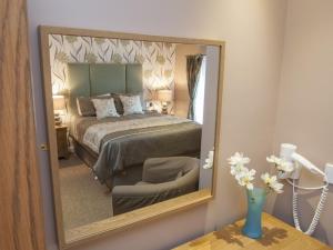 TarlandThe Commercial Hotel的镜子反射着一间卧室,卧室配有一张床和椅子