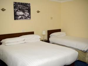 洛斯托夫特Park Hill Hotel的配有白色床单的酒店客房内的两张床