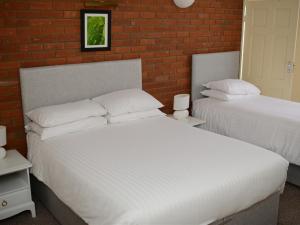 洛斯托夫特Park Hill Hotel的一间卧室设有两张床和砖墙