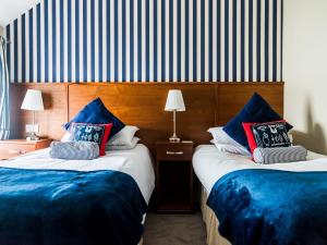 DonaghadeePier 36的两张位于酒店客房的床,配有蓝色枕头