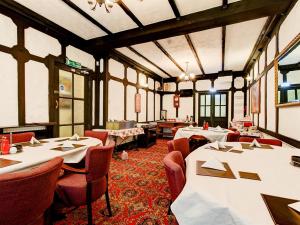 布莱克浦Thistle Dhu Guest House的餐厅设有白色的桌椅和窗户。