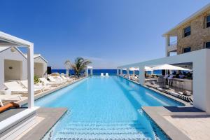 威廉斯塔德Saint Tropez Boutique Hotel的一个带椅子的游泳池,背景是大海