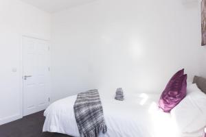 特伦特河畔斯托克Townhouse @ 76 Clare Street Stoke的卧室配有白色床和紫色枕头