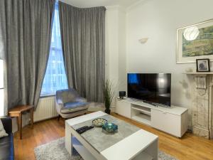 伦敦Spacious 1 Bed in West Kensington or Hammersmith的客厅配有平面电视和桌子。