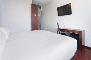 费尔盖拉什B&B HOTEL e Apartamentos Felgueiras的卧室配有白色的床和电视。