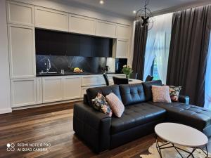 扎莫希奇Stara Wartownia的一间带黑色沙发的客厅和一间厨房
