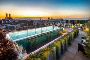 慕尼黑Mandarin Oriental, Munich - Germany's Best City Hotel 2024的一座享有日落美景的建筑屋顶上的游泳池