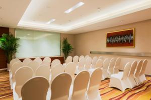 南京南京水游城假日酒店的一间会议室,配有白色的椅子和屏幕